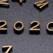o ano de 2020 em números dorados em um fundo preto. Com letras douradas espalhadas.
