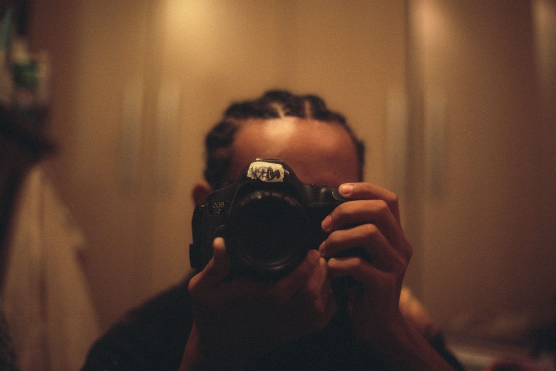 Homem negro ajustando a lente de uma câmera fotográfica com o automático desligado
